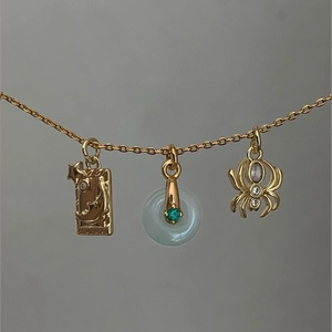 Golden necklace featuring moon star plaque, green jade ring, and spider charms