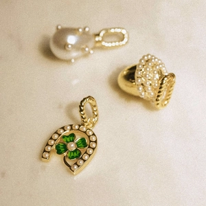 Detail of horseshoe pendant with green enamel four-leaf clover and pearl accents