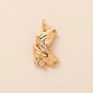 Detailed view of gold pendant featuring hands holding sparkling clear zircon stones