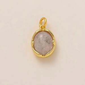 Detailed view of an oval pink natural stone pendant with gold-plated edge and top ring