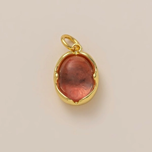 Gros plan détaillé d'un pendentif ovale en pierre brun-rouge avec cadre plaqué or 18 carats