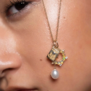 Golden necklace with passport pendant, colorful opal crescent, and large white pearl charm