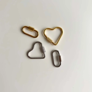 Detailed macro of gold and silver heart-shaped carabiner locks with knurled screw mechanisms