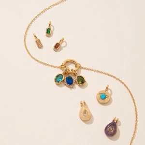 Collier en acier doré avec pendentifs pierres de naissance colorées sur fond beige