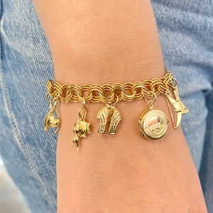 Bracelet double chaîne vintage plaqué or 18 carats avec cinq breloques sur fond denim