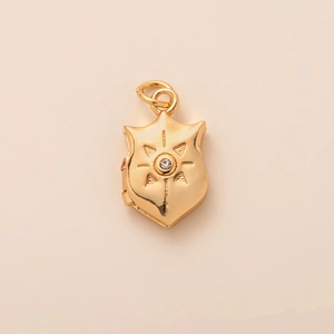 Macro shot of gold shield pendant featuring sunburst engraving and center zircon stone