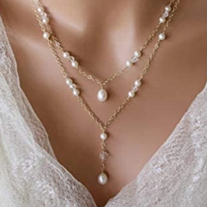 Detail van een dubbellaagse gouden ketting met barokparels op model in kantwerk