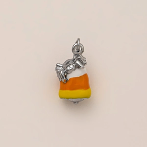 Detailed close-up of a silver spider on a colorful candy corn enamel pendant charm