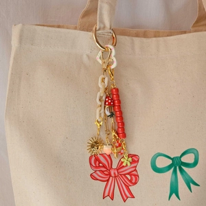 DIY 18K gold plated keychain featuring red ribbon bow and sun pendant on canvas bag