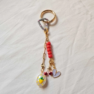 Macro shot of 18K gold plated keychain charm with cherry pendant and colorful beads