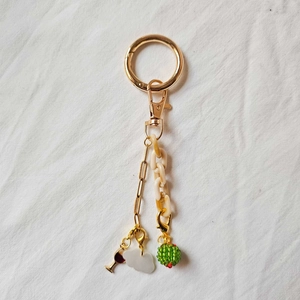 Detail of 18K gold-plated keychain with red wine cup, cloud charm, and green beaded ball