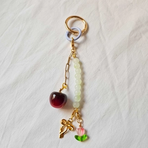 Detail of 18K gold plated keychain with red cherry, tulip charms and green beads