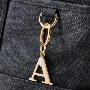 Detail of 18K gold plated letter A charm with faux pearls on grey canvas bag