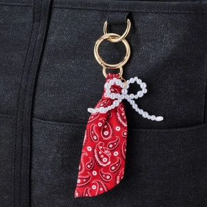 Detail of red floral silk ribbon keychain with white pearl bow on black canvas bag