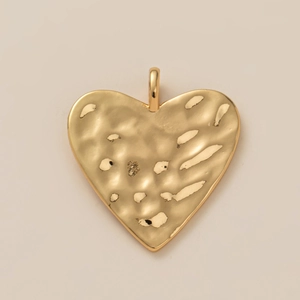 Detailopname van een gouden hartvormige hanger met gehamerde textuur en gepolijste afwerking