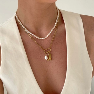 Detail van dubbellaagse gouden ketting met parels en een hanger van een cowboylaars