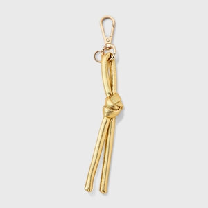 Dettaglio di un portachiavi in pelle dorata con nodo e chiusura a moschettone lucida oro 18K