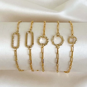Five-piece gold paperclip chain bracelet set featuring geometric charms and hammered links