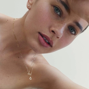 Close-up of double-layered 18K gold plated necklace with bar and disk pendants