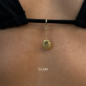 Macro-opname van een gouden schelphanger aan een zwarte bikini voor een zomerse strandstijl