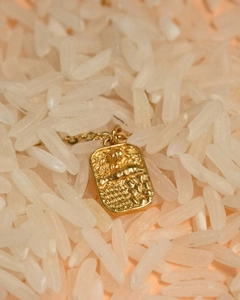 Macro view of 18K gold plated rectangular pendant with embossed relief texture