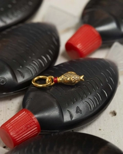 Macro detail of a 18K gold fish pendant with red ring accents on decorative props
