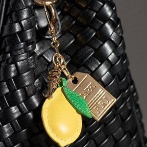 Bolso trenzado negro con dijes de limón, pez de metal y etiqueta dorada de Capri
