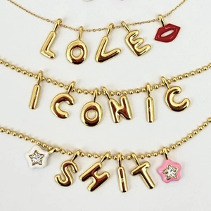 Dettaglio di tre collane placcate oro con ciondoli a lettere LOVE e ICONIC