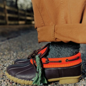 Détail d'une botte de pluie en toile orange avec semelle classique en caoutchouc brun