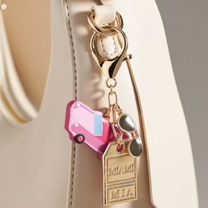 Detalle de un llavero colorido con iconos de coche y gafas en un bolso de cuero beige