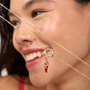 Detail of 18K gold necklace with micro-paved letter B and red enamel chili charms