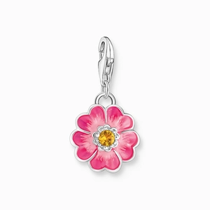 Macro view of a 18K gold flower charm with pink enamel petals and a yellow crystal core