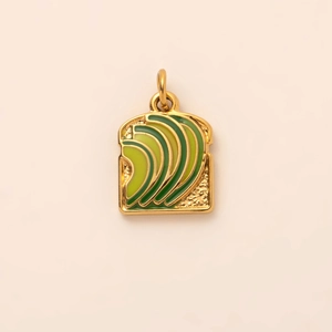 Macro detail of toast and avocado pendant with 18K gold plating and green enamel finish
