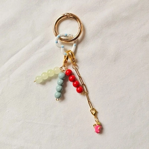 Detail of DIY keychain featuring golden ring, blue polka dot heart, and pink pig charm