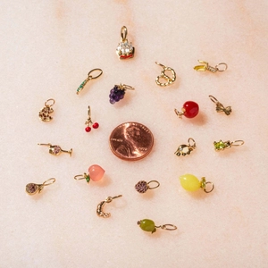 14K gold plated fruit charms set with cherry and grape designs next to a penny