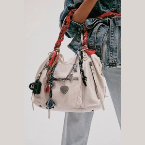 Detail of cream leather hobo bag featuring floral silk scarf and multiple metal pendants