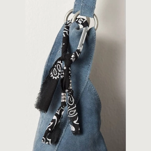 Detail of blue suede bag with silver ring and paisley silk scarf accessory