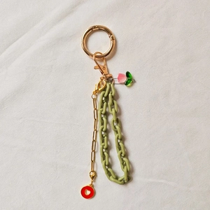 Detail of DIY keychain with green acrylic chain, red heart pendant and pink tulip charm