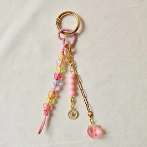 Detail of DIY keychain with pink suede cord, rainbow heart beads, and peach pendant charm