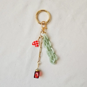 Detail of 18K gold plated keychain with red heart, green chain and jam jar charms