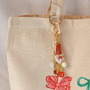 DIY charm keychain with pink heart lock, resin chain, and fur pompom on canvas bag