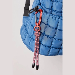 Detail of blue quilted puff bag with red metal carabiner and tricolor braided rope