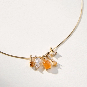 14k gold plated snake chain necklace with opal and zircon charms on a textured background