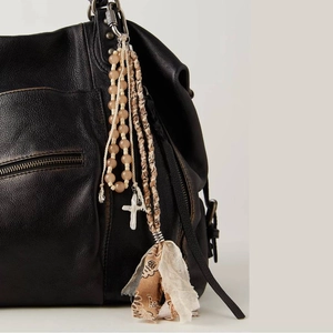 Bohemian bag charm with beads and tassels hanging on a premium black leather bag