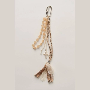 Detailed close-up of bohemian keychain with yellow beads and pearl cross charm