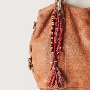 Bohemian bag charm with red beads and dark red tassels on a brown leather handbag