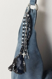Detailed close-up of bohemian bag pendant with beads, woven rope and floral tassel