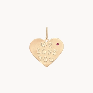 Detalle macro de un colgante de corazón chapado en oro de 14K con relieve WE LOVE YOU