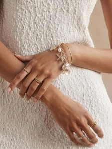 Detail von 18K Gold Seestern und Muschel Armband mit passenden Ringen am Model