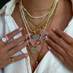Detalle de joyas a capas con colgantes de corazón coloridos textura azúcar y perlas